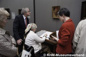 Photograph of a groups of people observing the Portrait of the Ferrara Court Jester Gonella and 3D relief. Copyright KHM-Museumsverban